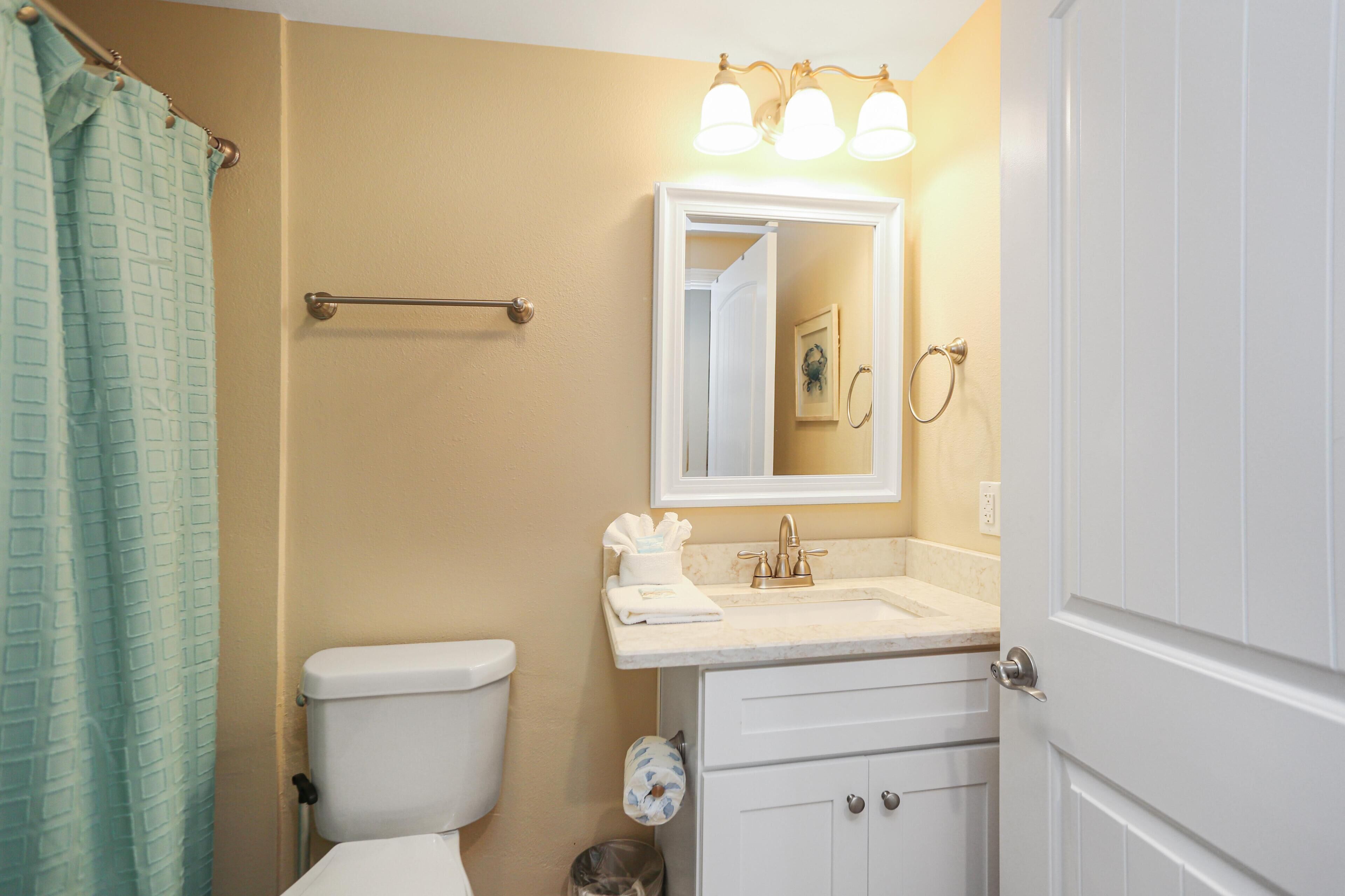 A bathroom with a toilet, sink, and mirror.