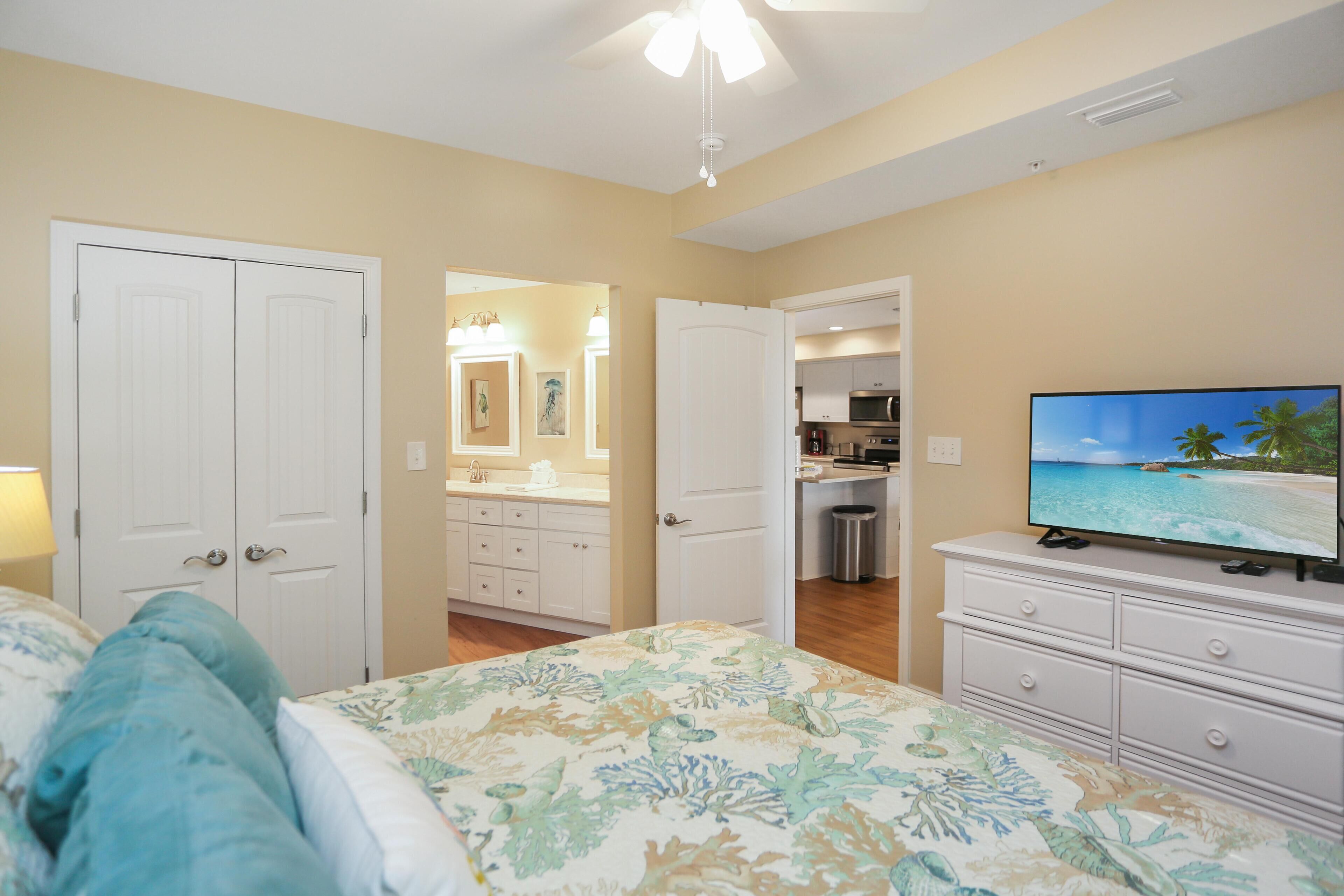 A bedroom with a bed, a dresser, and a television displaying a beach scene.