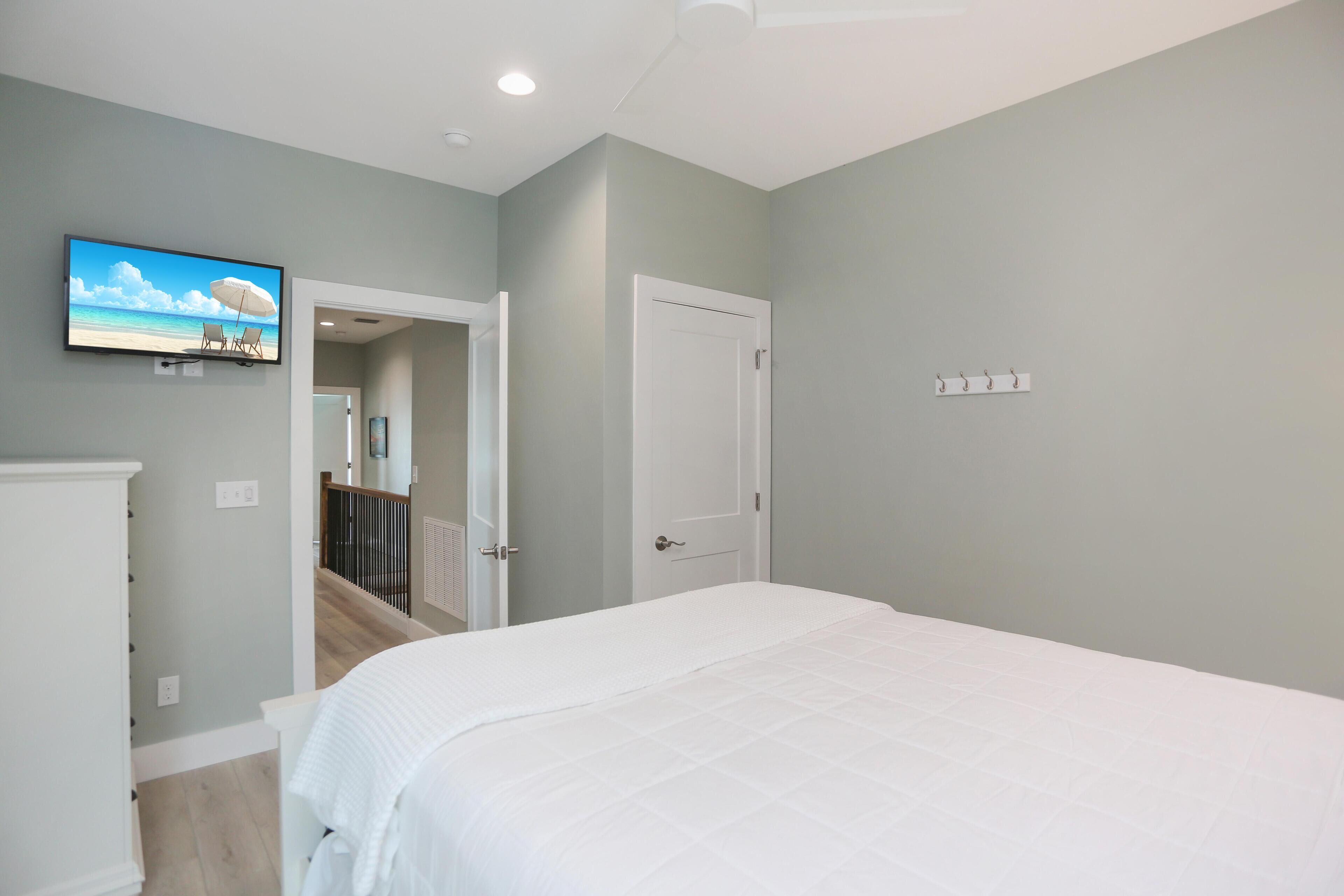 A bedroom with a bed, a television on the wall, and a door leading to another room.