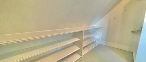 A room with a sloped ceiling and built-in white shelving units against the wall.