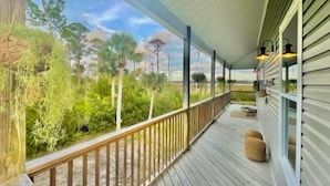 A covered porch with a wooden railing, a bench, and a hanging basket. - Otter Cove (Port St. Joe)