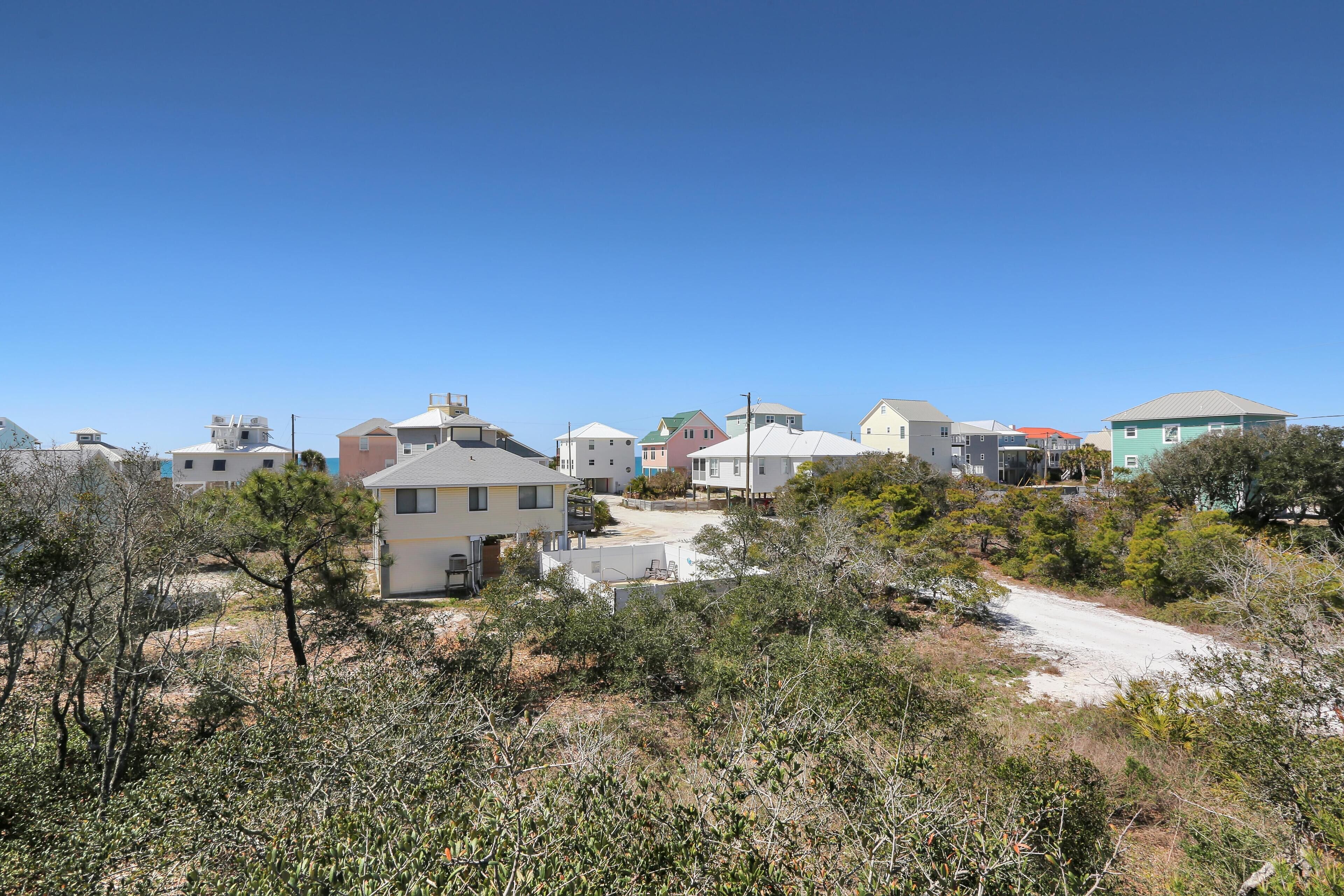 A residential area with houses, a dirt road, and sparse vegetation.