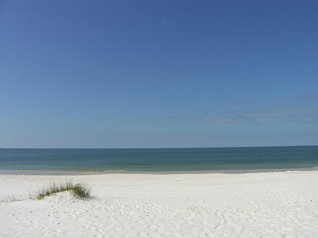 A beach with white sand and a clear blue sky.