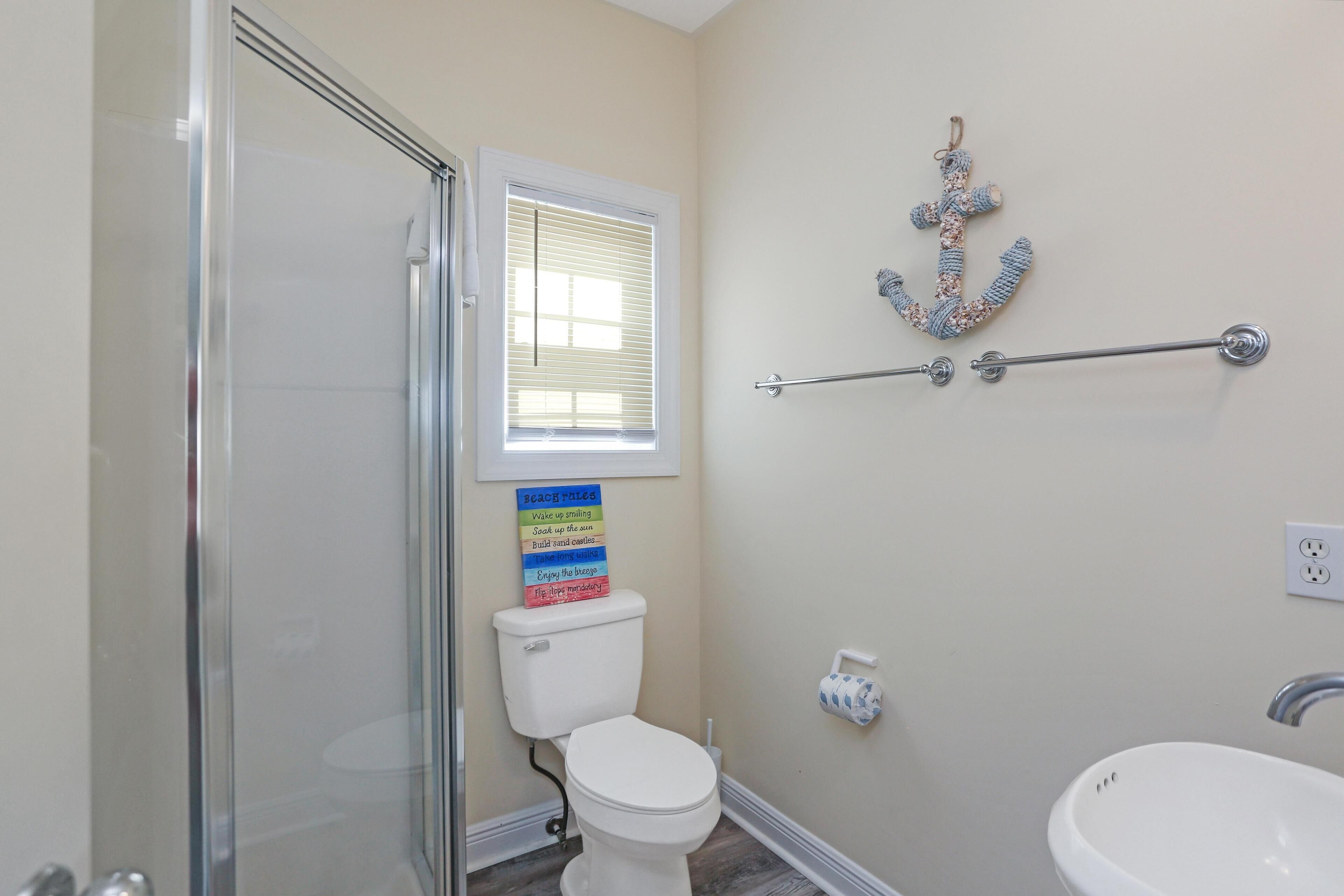 Ein Badezimmer mit Duschkabine, Toilette, Waschbecken und Handtuchhalter.