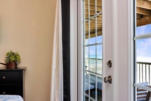 A room with a sliding glass door leading to a balcony with a wooden deck and a view of the beach. - The Chill Inn (Port St. Joe)
