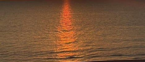 A sunset over a calm sea with a visible horizon line.