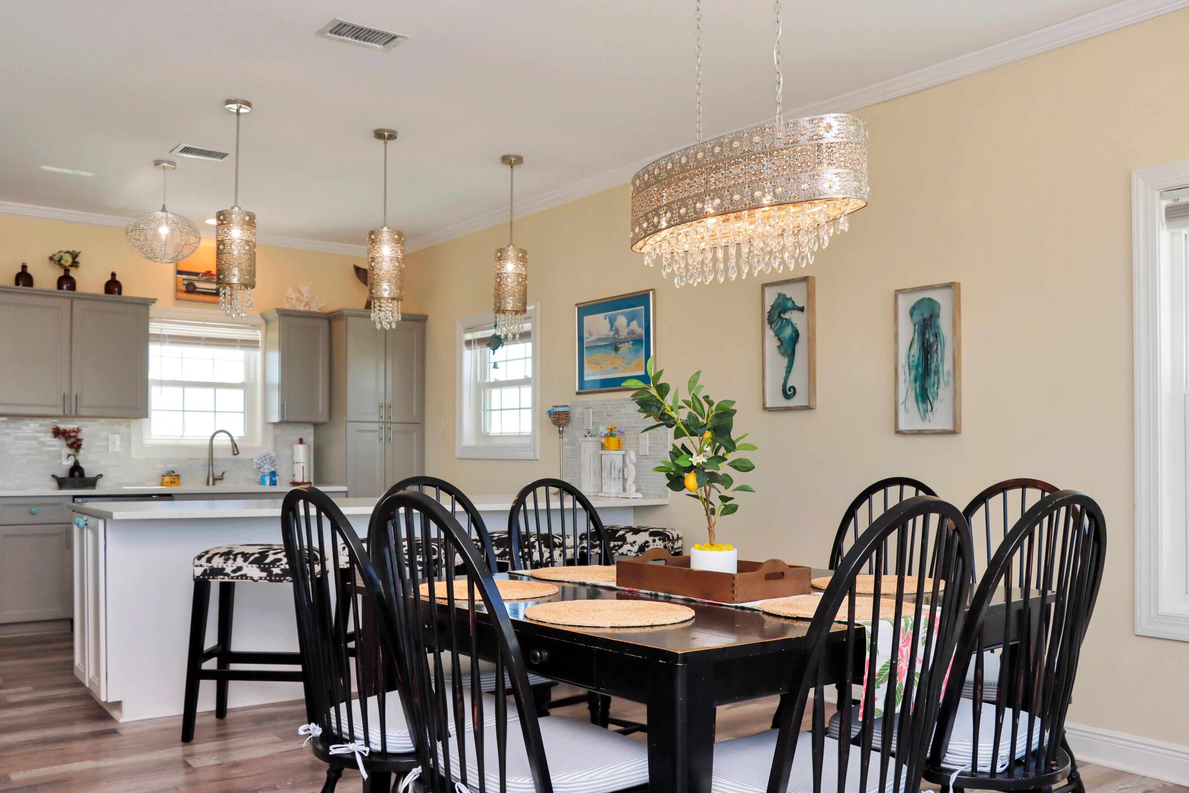 A dining area with a black table and chairs, a chandelier, and artwork on the walls.