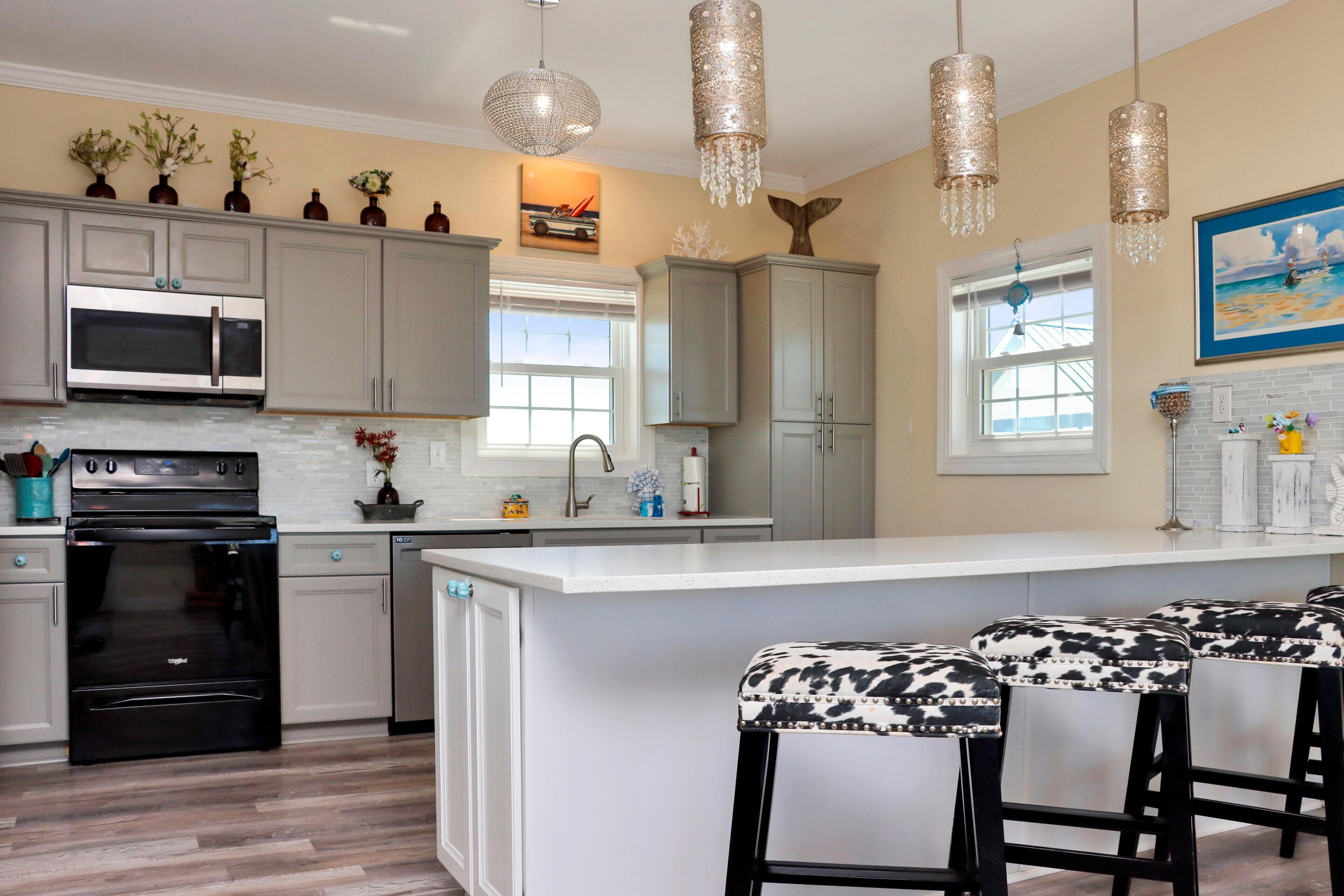 A kitchen with a central island, bar stools, stainless steel appliances, and decorative items.