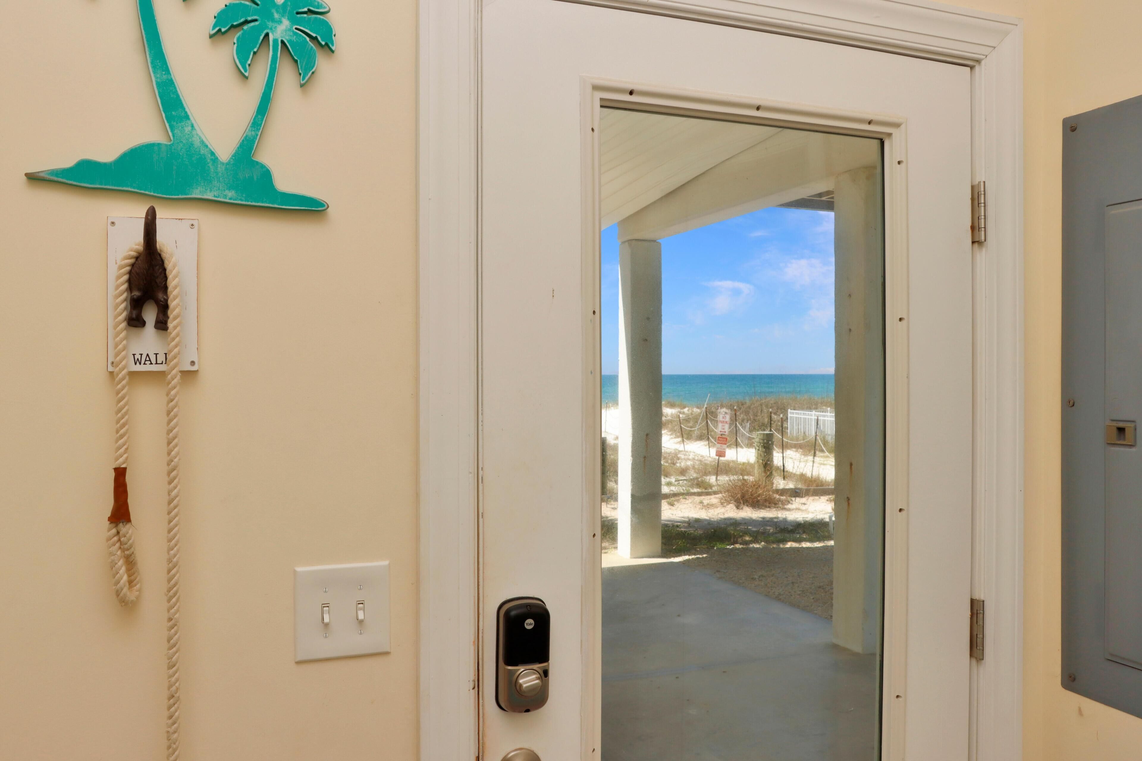 A door leading to a balcony with a view of the beach and ocean.