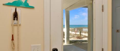 A door leading to a balcony with a view of the beach and ocean.