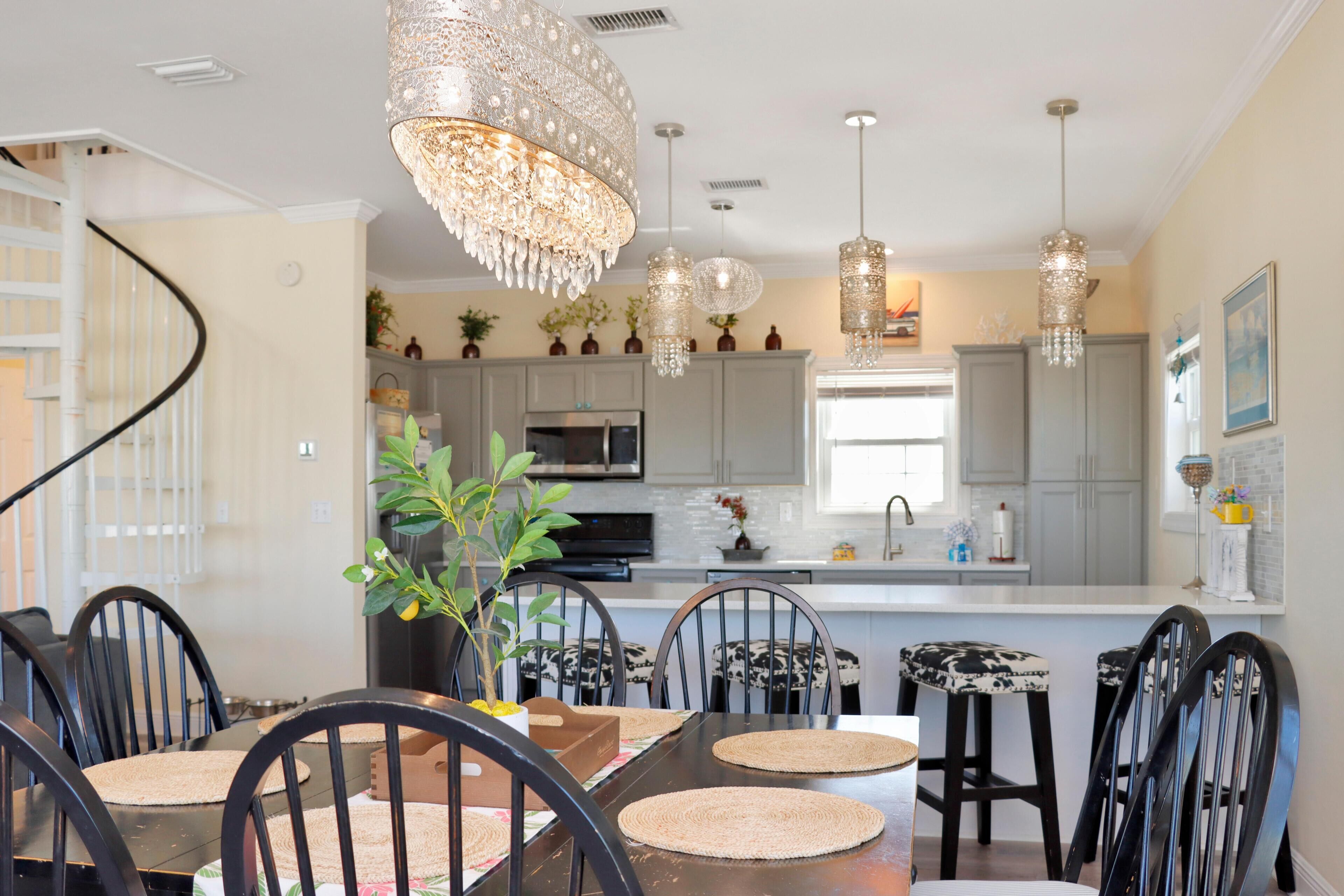 A dining area with a central table, chairs, and a chandelier.