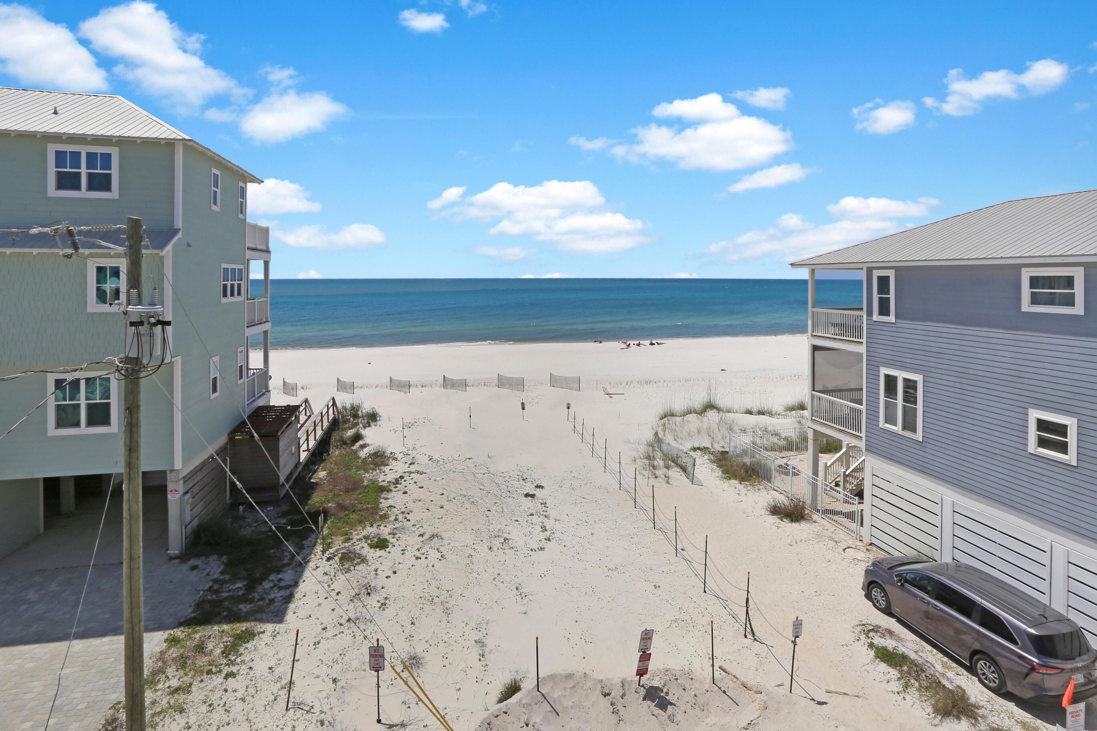 A beachside property with a sandy beach, a clear blue sky, and a view of the ocean.