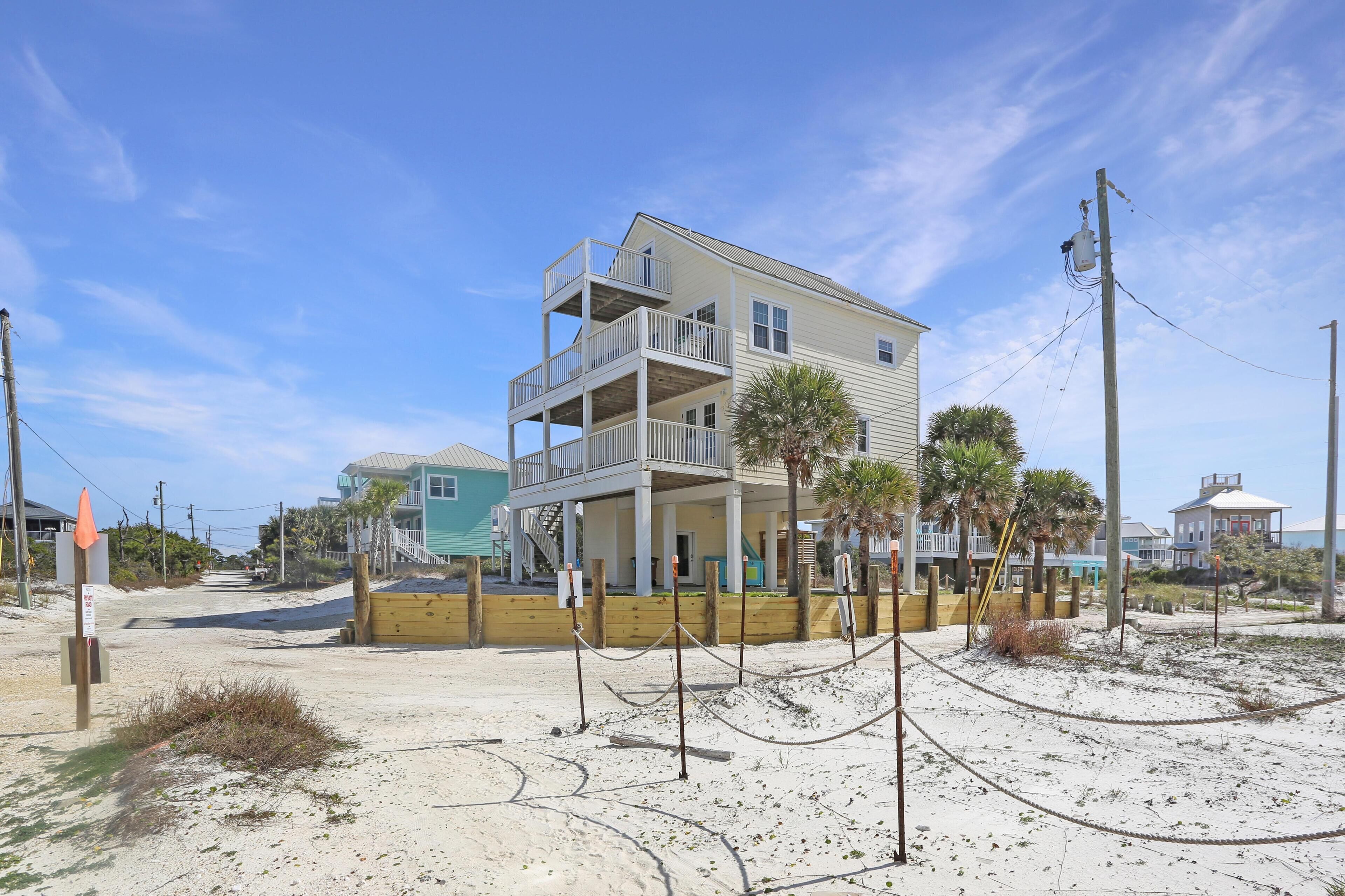 A beachfront property with a multi-story building, a sandy beach, and a clear sky.