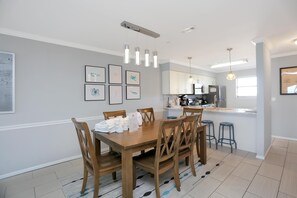A modern kitchen with white cabinets, a central island, and pendant lighting. - The Hidden Pearl (Port St. Joe)
