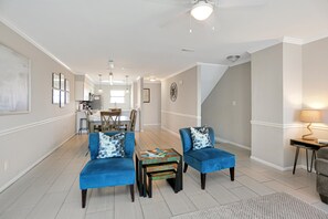 A spacious living area with a dining table, blue armchairs, and a small coffee table. - The Hidden Pearl (Port St. Joe)