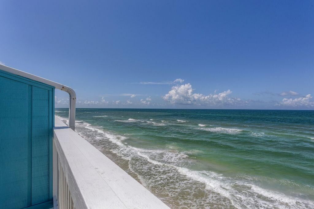 Une vue sur l’océan depuis un balcon doté d’une rambarde bleue.