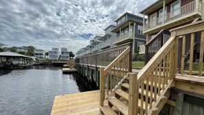 A waterfront property with wooden decks, a dock, and a row of multi-story buildings with balconies.