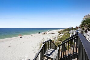 A beach with a wooden staircase leading down to the sand, a red umbrella, and a clear view of the ocean. - Sun Chaser (Port St. Joe)