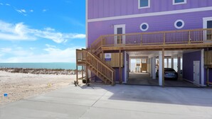 A two-story building with a purple exterior, a wooden balcony, and a car parked inside. - Beach Fantasies A (Port St. Joe)