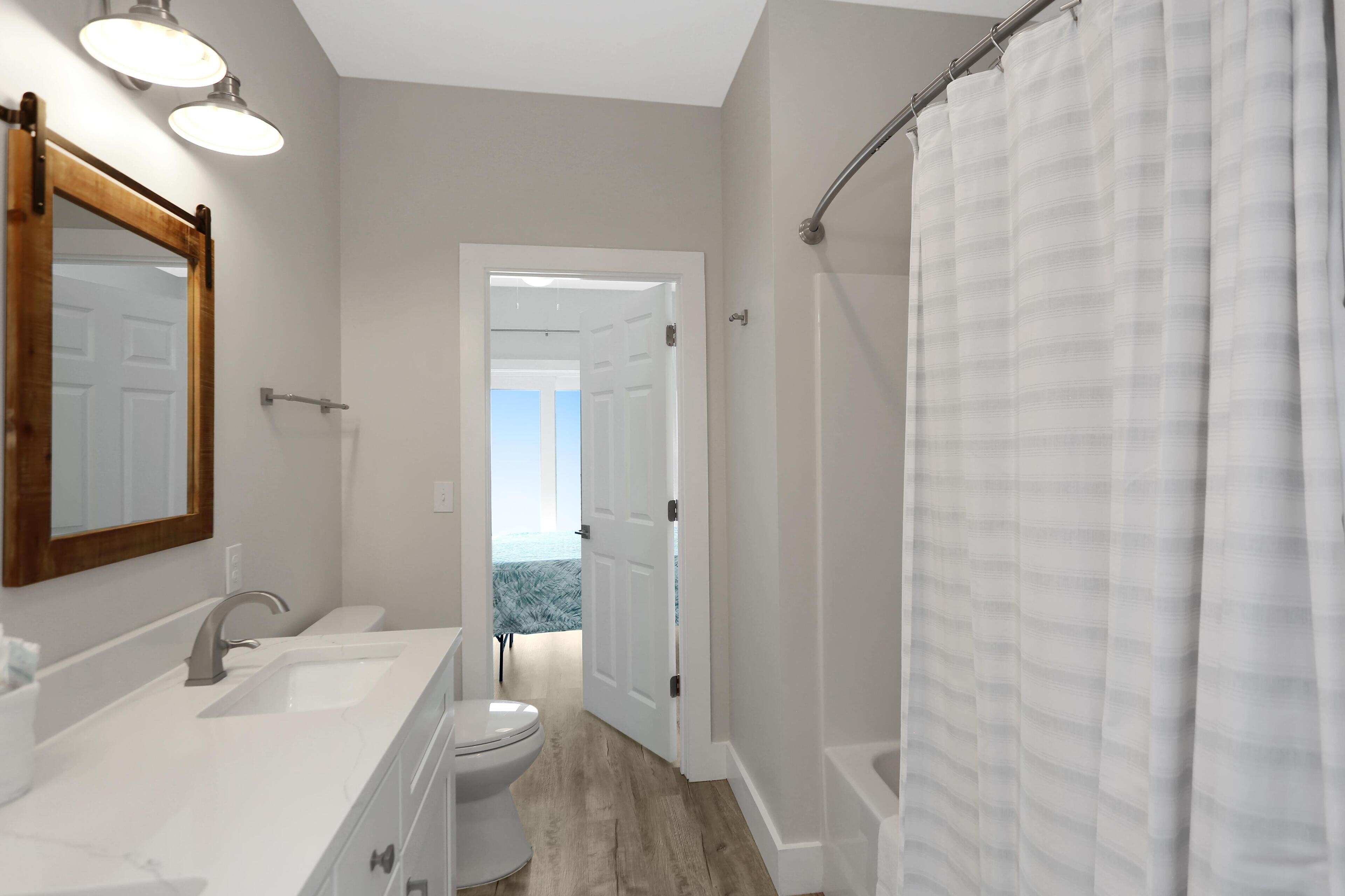 A bathroom with a large mirror, two sinks, a toilet, and a shower.