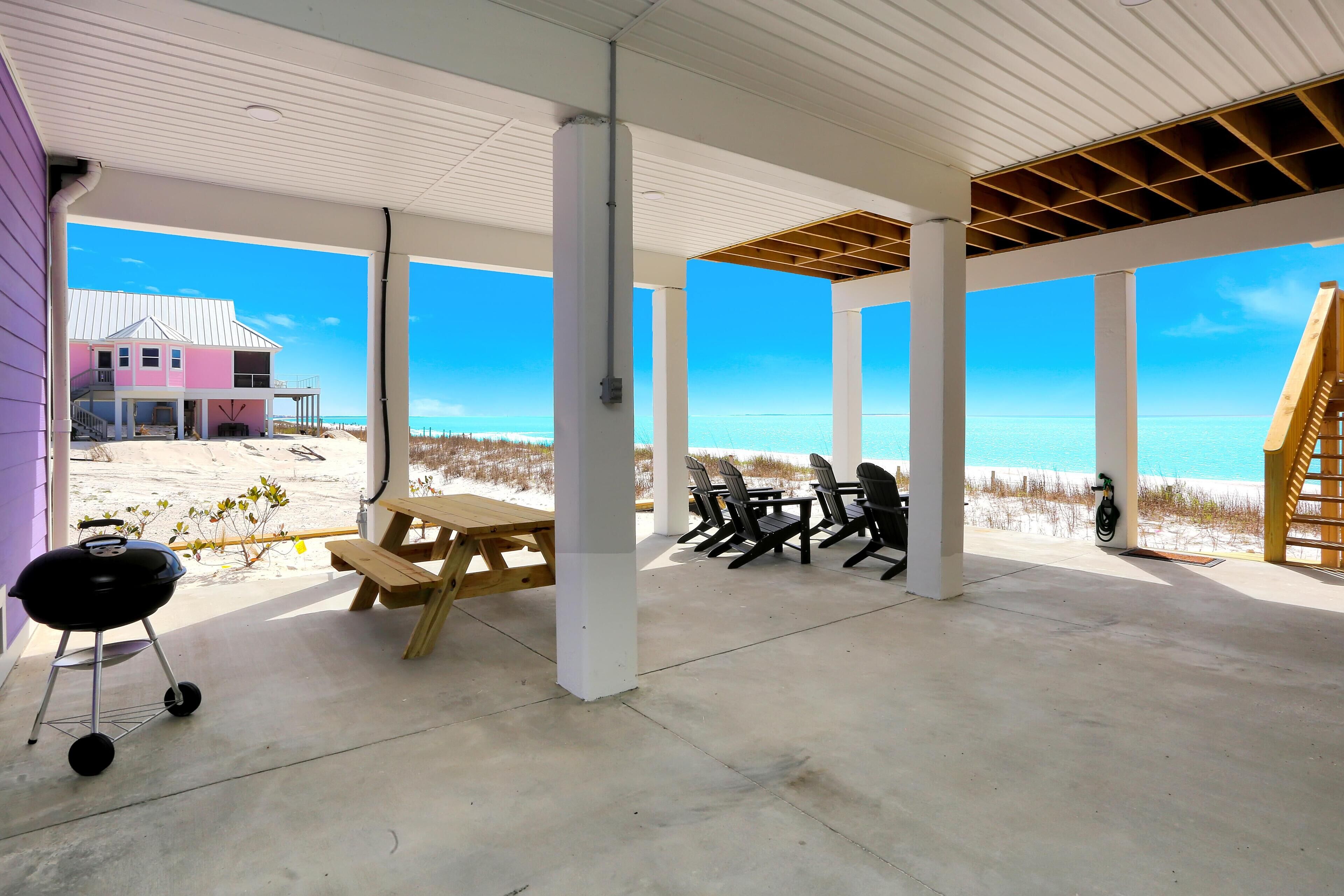 An outdoor patio with a concrete floor, a picnic table, and chairs.