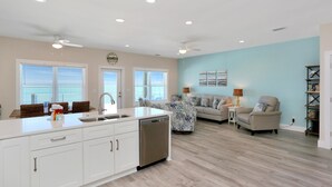 A spacious kitchen with a dishwasher, a dining area with a table and chairs, a living room with a sofa and a coffee table, and a ceiling fan. - Beach Fantasies B (Port St. Joe)