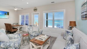 A living room with a ceiling fan, a dining table with chairs, a sofa, and a coffee table. - Beach Fantasies B (Port St. Joe)