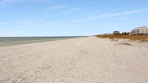 Une vaste plage de sable, un ciel dégagé et un bâtiment situé sur la droite.