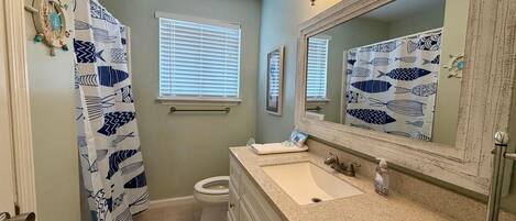 A bathroom with a sink, toilet, and a mirror with a fish pattern backsplash.