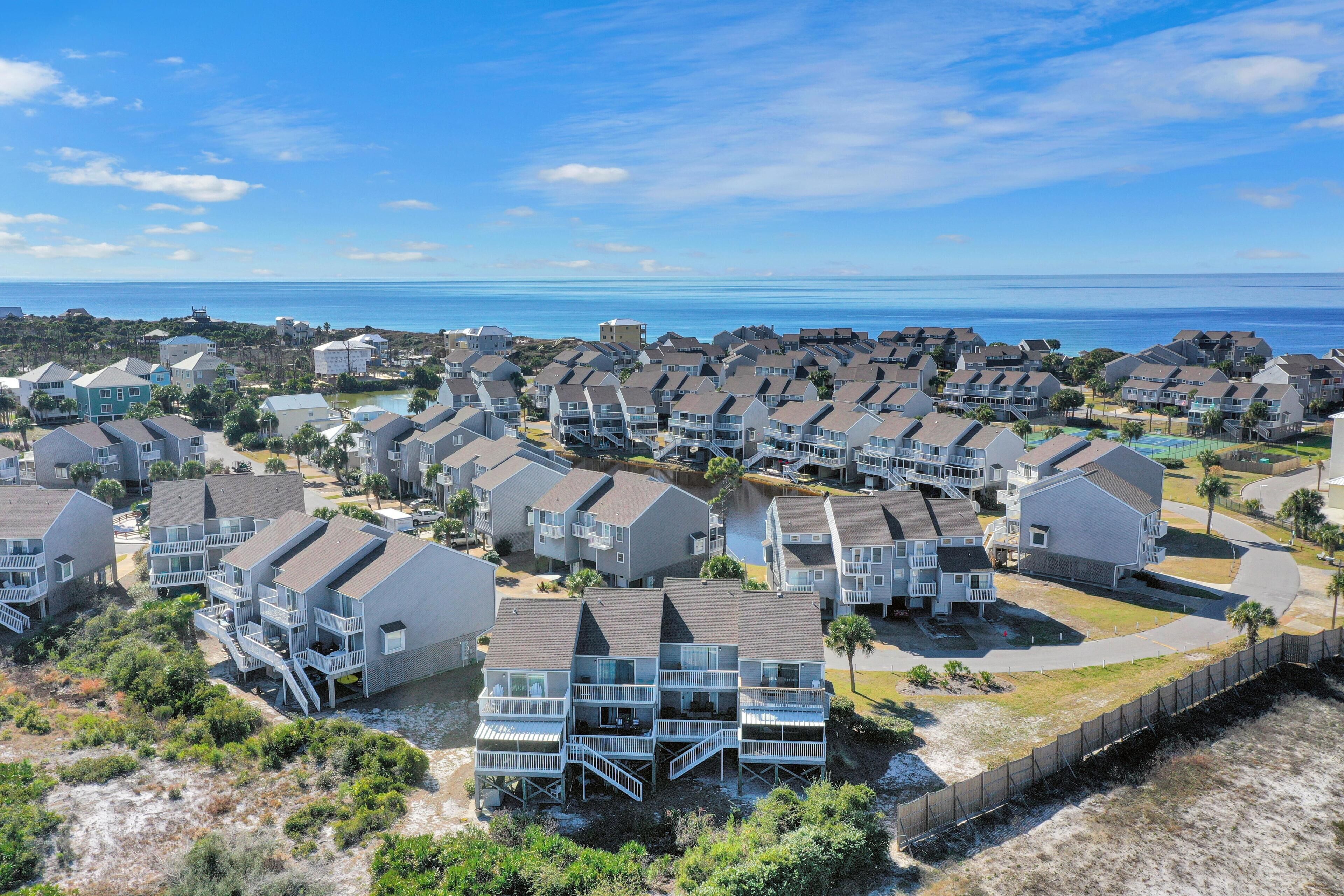 A coastal residential area with multi-story houses, some with balconies, and a clear view of the ocean.