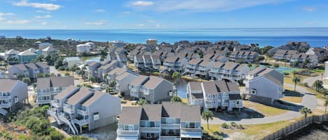A coastal residential area with multi-story houses, some with balconies, and a clear view of the ocean.
