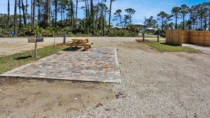 A paved area with a picnic table, surrounded by a gravel path and a wooden fence.