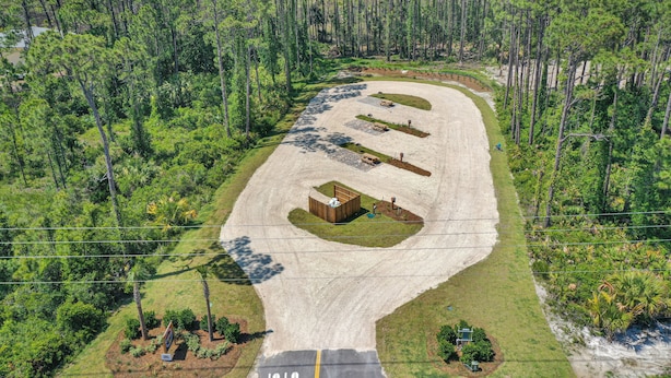An aerial view of a parking lot with a building, surrounded by dense forest. - Bay Destiny RV Lot 2 (Port St. Joe)