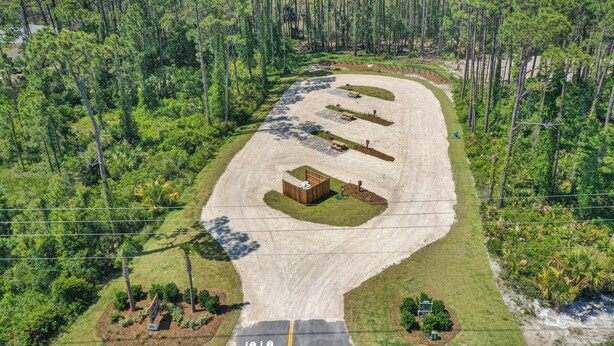 Vista aérea de un estacionamiento con un edificio, rodeado de un bosque denso.