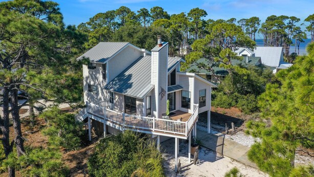 A coastal house with a deck, surrounded by pine trees and a view of the sea. - A Swell Life (Port St. Joe)