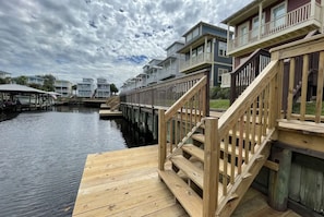 A waterfront property with wooden decks, a dock, and a row of multi-story buildings with balconies. - Waterside Village Condo 203 (Port St. Joe)