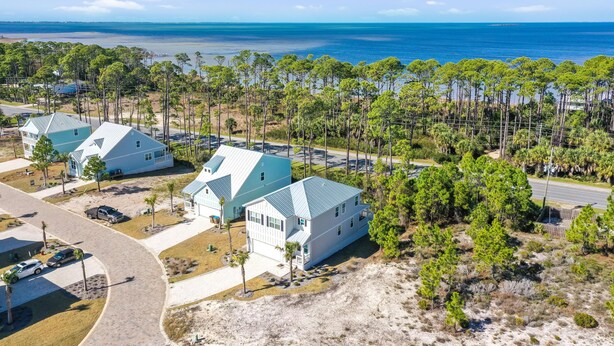 A coastal residential area with houses, a paved road, and a beach in the background. - Just Beach Baby! (Port St. Joe)
