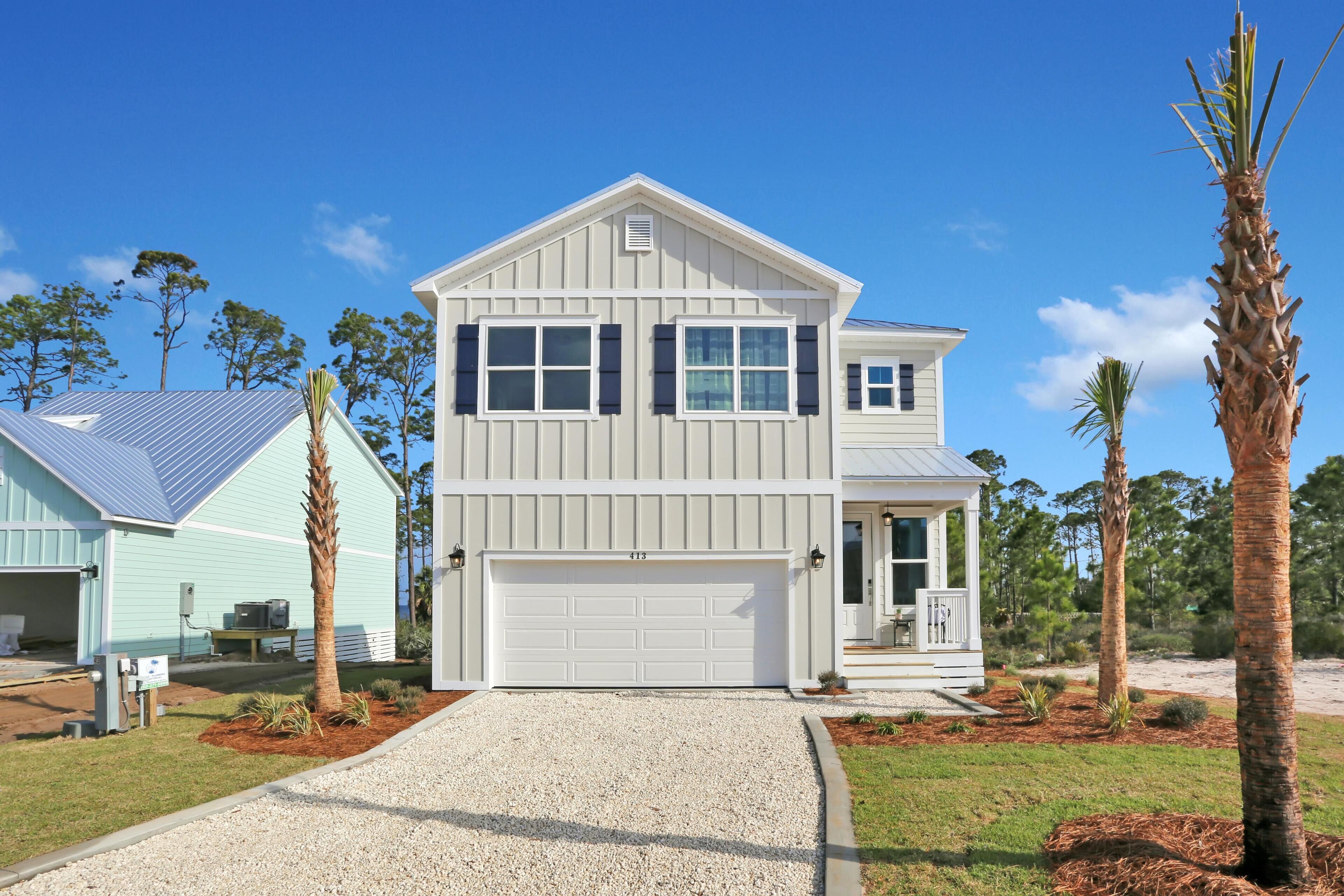 A two-story house with a white garage door, a covered porch, and a gravel driveway.