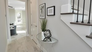 A hallway with a glass table, a potted plant, and framed artwork on the wall. - Just Beach Baby! (Port St. Joe)