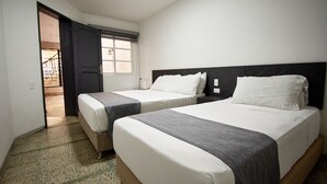 Una habitación de hotel con dos camas, una puerta que da a un balcón y una ventana con persianas.
