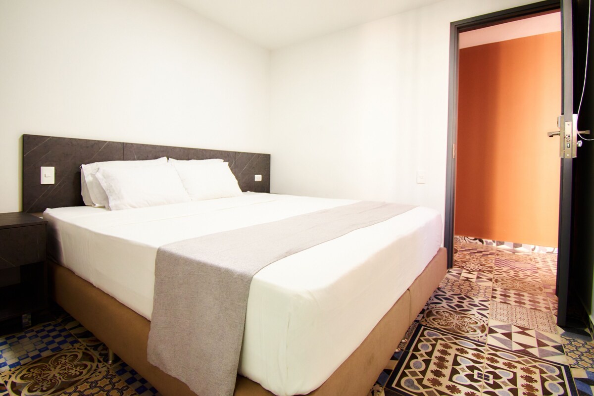 Ein Hotelzimmer mit einem Bett, einem Nachttisch, einer Tür und einem Bodenbelag mit Muster.