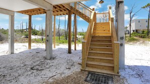 A wooden staircase leading to a covered outdoor area with a metal grate at the bottom. - Cape Bear (Port St. Joe)