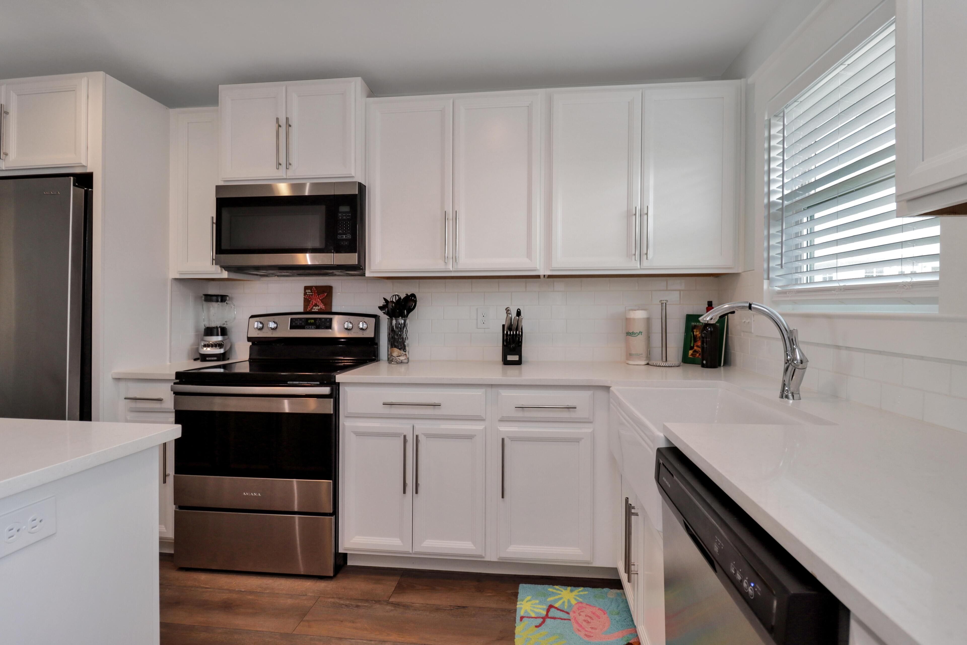 A modern kitchen with white cabinets, stainless steel appliances, and a dishwasher.
