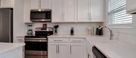 A modern kitchen with white cabinets, stainless steel appliances, and a dishwasher.