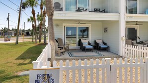 A two-story residential building with a balcony, a sign indicating 'Pristine Properties', and a white picket fence. - Wine Down (Port St. Joe)