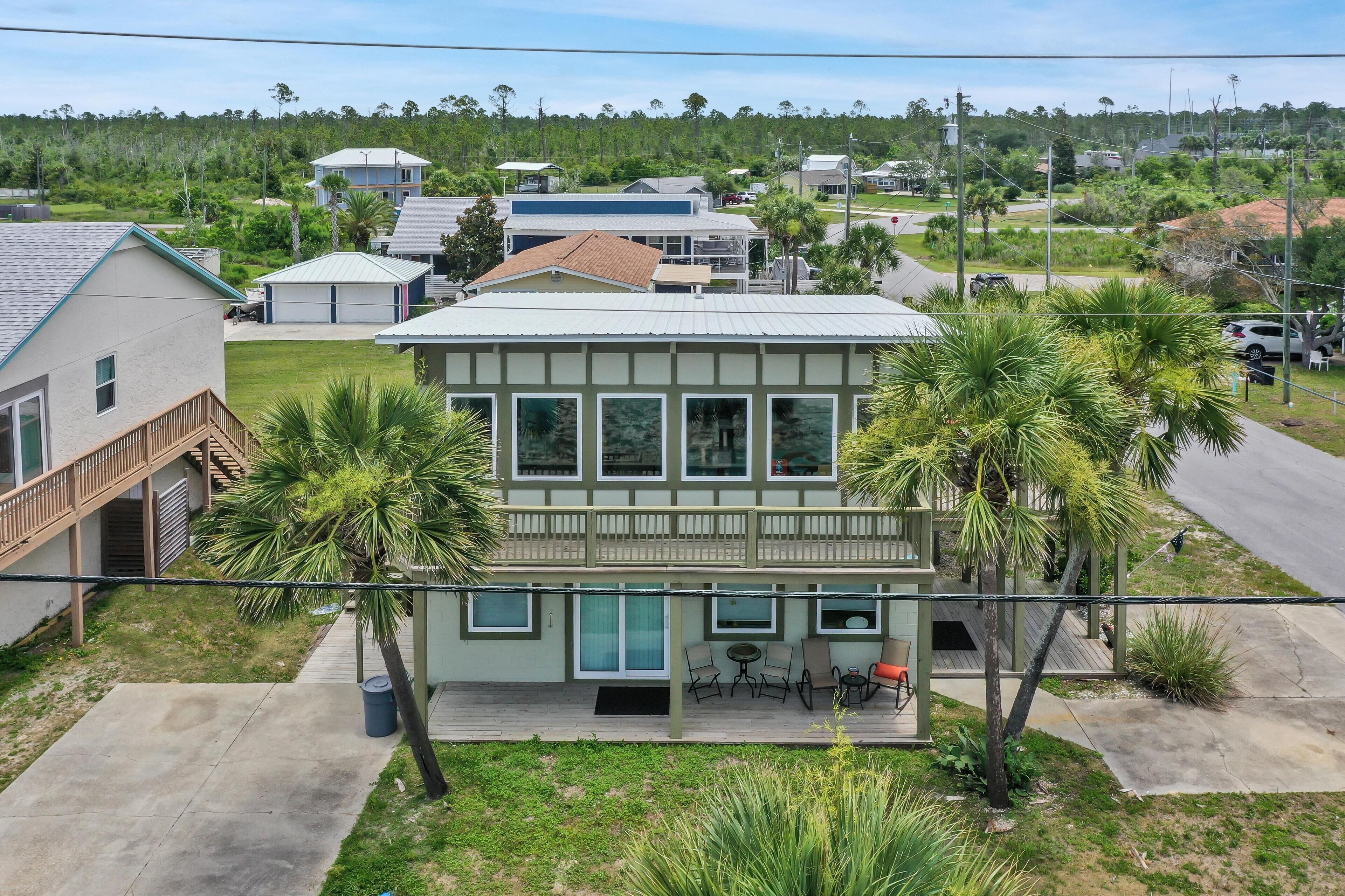 A two-story house with a balcony, large windows, and a small patio area with outdoor seating.