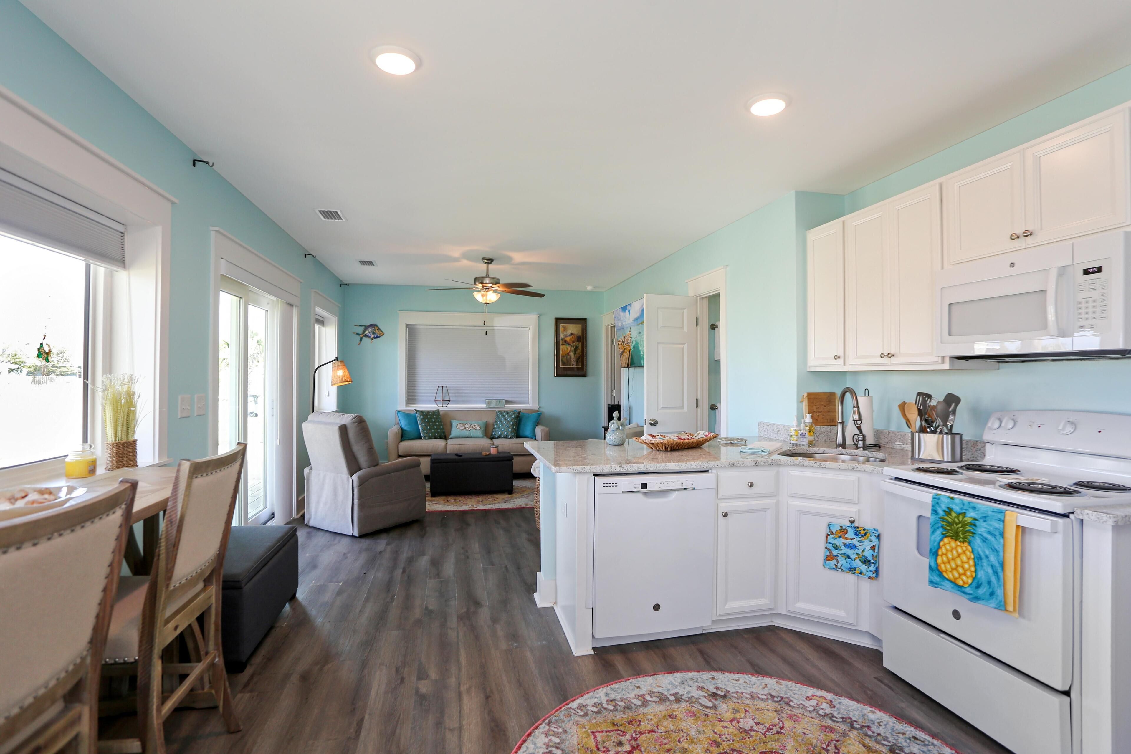 A kitchen with white cabinets, a microwave, and a stove. There is a dining area with a table and chairs.