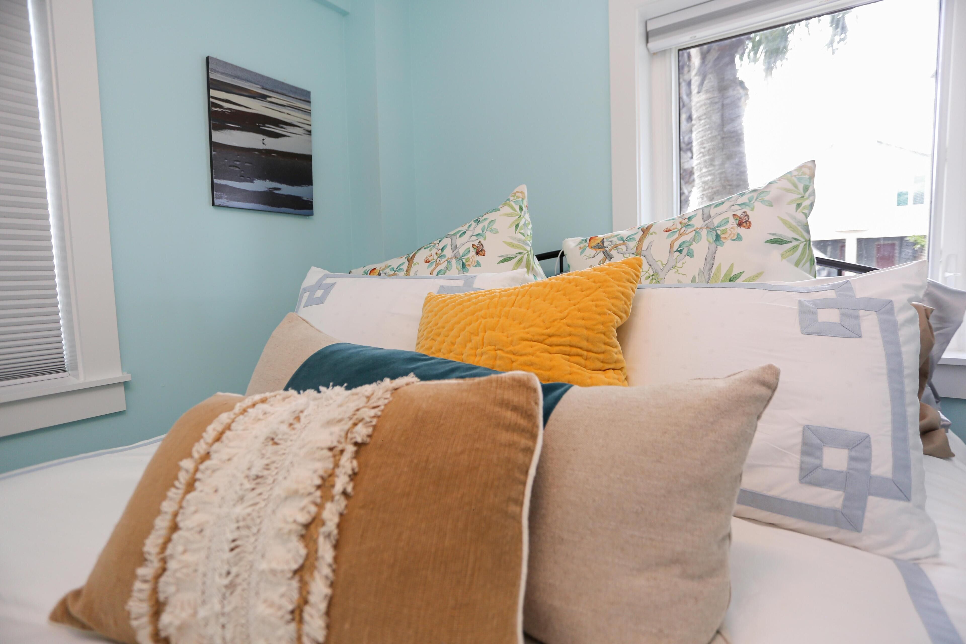 Ein Bett mit vielen Kissen und einem gerahmten Bild an der Wand.