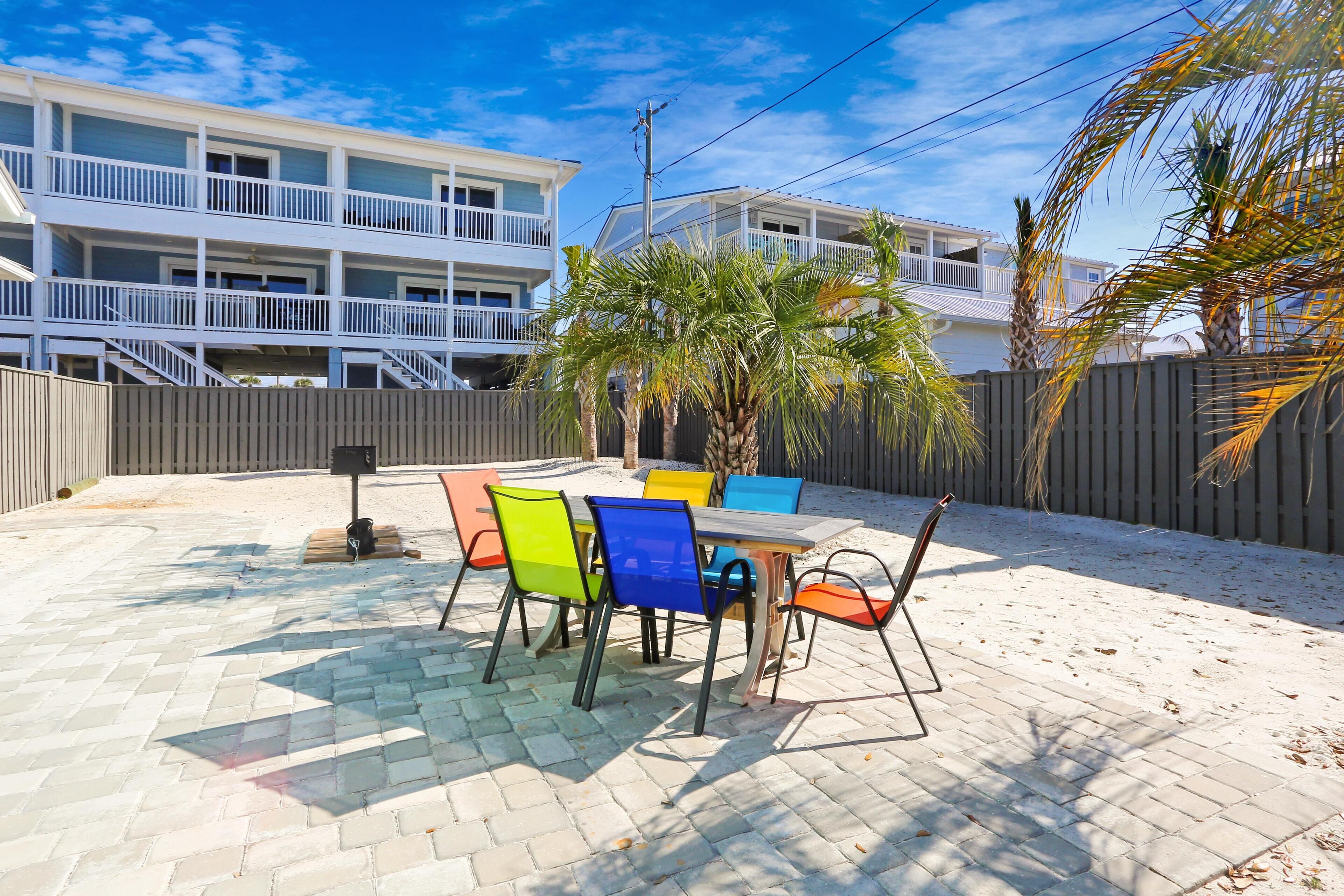 A patio with a table and chairs, a wooden fence, and a building with balconies in the background.