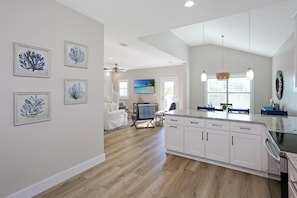 A spacious kitchen with white cabinets, a large island, and a dining area with a view. - Second Chance (Port St. Joe)
